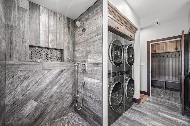 laundry room featuring cabinets and stacked washing maching and dryer