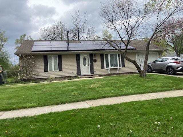 ranch-style home featuring a front lawn, a garage, and solar panels