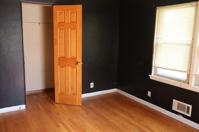 unfurnished bedroom with multiple windows, a closet, and light wood-type flooring