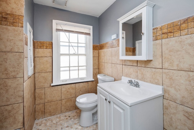 bathroom with tile walls, vanity, and toilet