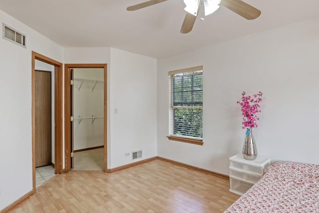 bedroom featuring ceiling fan, a walk in closet, a closet, and hardwood / wood-style floors