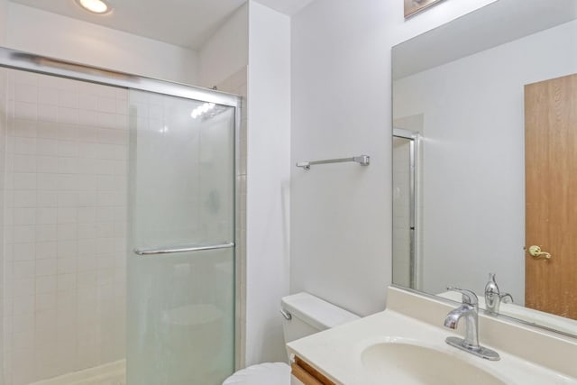 bathroom featuring toilet, vanity, and a shower with door