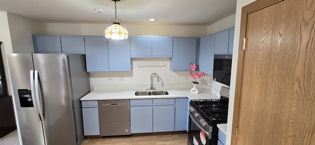 kitchen featuring hanging light fixtures, blue cabinetry, stainless steel appliances, light hardwood / wood-style floors, and sink