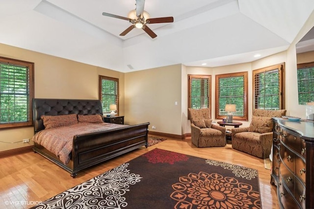 bedroom featuring light hardwood / wood-style floors, a raised ceiling, and ceiling fan