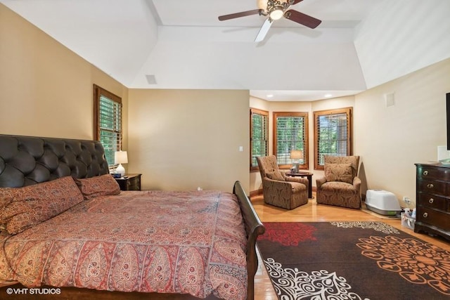 bedroom featuring vaulted ceiling, a tray ceiling, ceiling fan, and light hardwood / wood-style floors