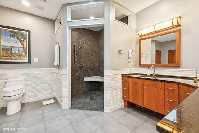 bathroom with vanity, toilet, tile patterned flooring, and a tile shower