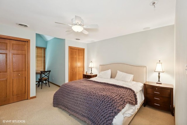 carpeted bedroom featuring multiple closets and ceiling fan