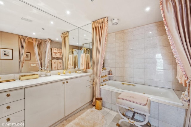 bathroom with tile patterned flooring, vanity, tiled bath, and tile walls