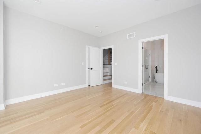 unfurnished bedroom featuring light hardwood / wood-style floors and connected bathroom