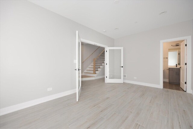 empty room featuring light wood-type flooring and french doors