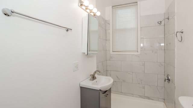 bathroom featuring a tile shower, toilet, and vanity