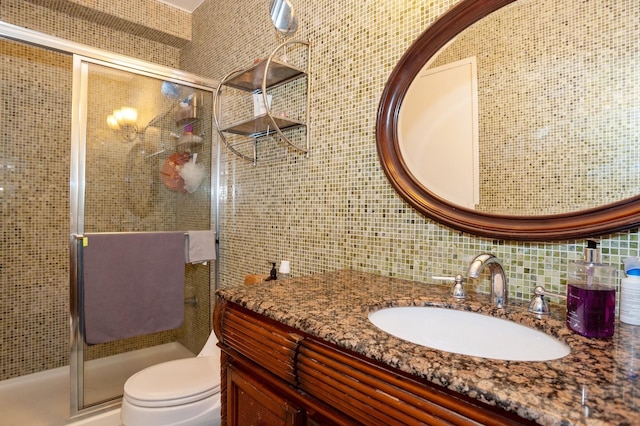 bathroom with toilet, decorative backsplash, a shower with door, vanity, and tile walls