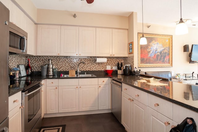 kitchen with tasteful backsplash, white cabinets, pendant lighting, and appliances with stainless steel finishes