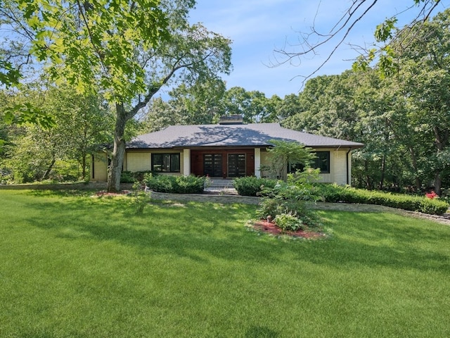 view of front of home with brick siding, a chimney, and a front lawn