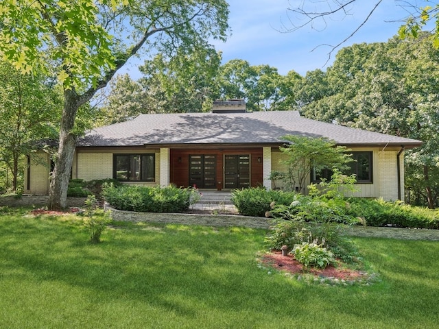 view of front of house featuring roof with shingles, a front lawn, and brick siding