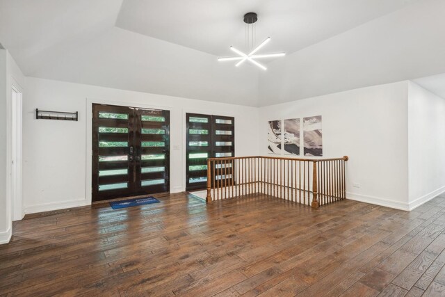 spare room with an inviting chandelier, french doors, wood-type flooring, and lofted ceiling