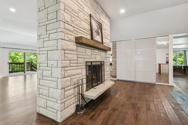 unfurnished living room with a stone fireplace, dark hardwood / wood-style flooring, and a healthy amount of sunlight