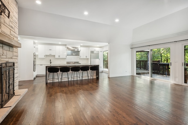 living room featuring sink, a fireplace, hardwood / wood-style flooring, and a towering ceiling