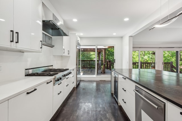 kitchen featuring white cabinetry, stainless steel appliances, a wealth of natural light, and wall chimney range hood