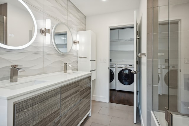 bathroom with dual vanity, tile walls, decorative backsplash, washer and dryer, and hardwood / wood-style flooring