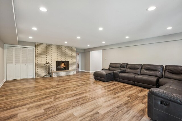 living room featuring light hardwood / wood-style floors, a brick fireplace, and brick wall