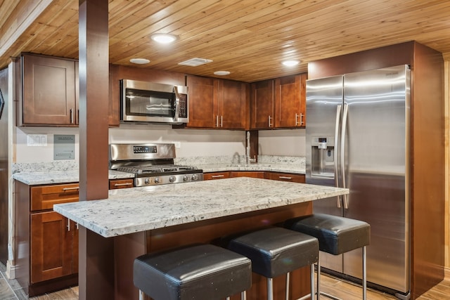 kitchen featuring a center island, appliances with stainless steel finishes, light wood-type flooring, and a kitchen breakfast bar