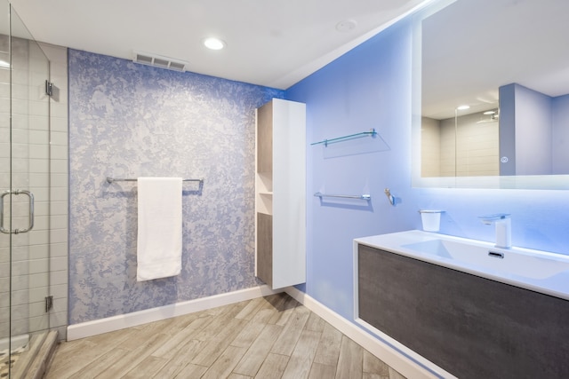 bathroom with a shower with shower door, vanity, and wood-type flooring