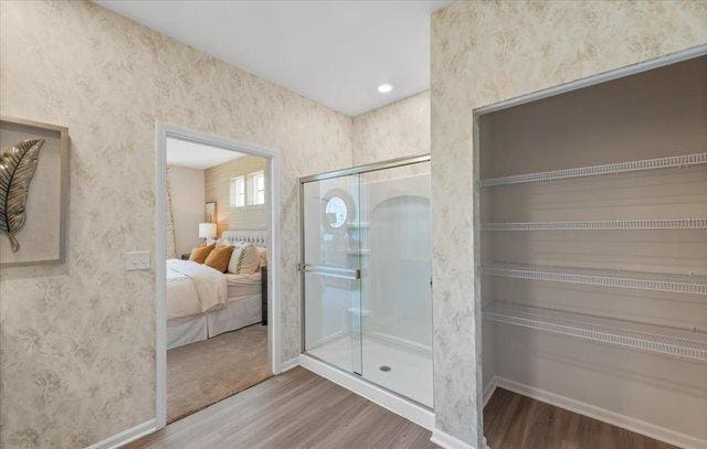 bathroom featuring baseboards, wood finished floors, and a shower stall