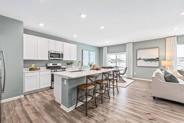 kitchen with an island with sink, appliances with stainless steel finishes, light countertops, and white cabinets