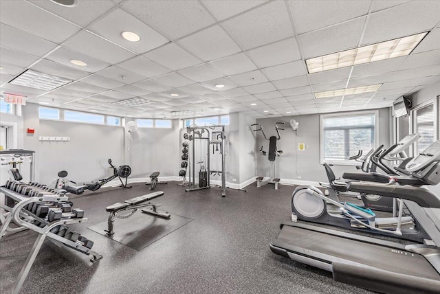 exercise room with a paneled ceiling and baseboards