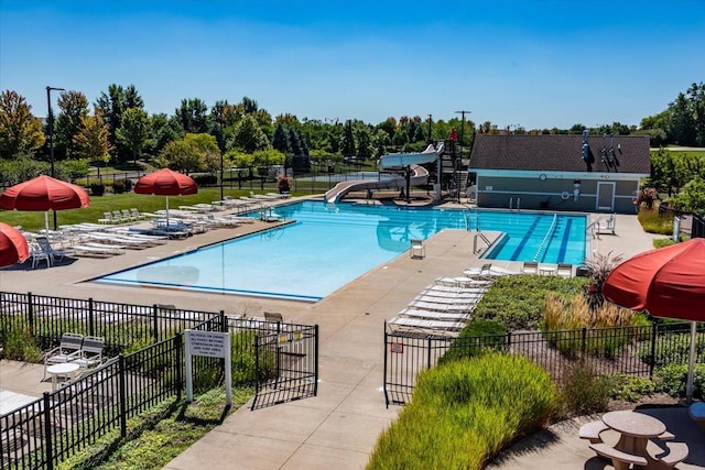 community pool featuring a patio, a water slide, and fence