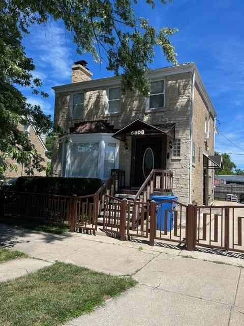 view of front of property with brick siding, fence, stone siding, and a chimney