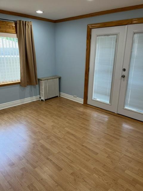 spare room with light hardwood / wood-style floors, radiator heating unit, and crown molding