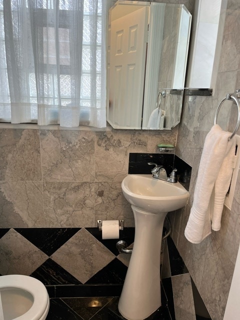 bathroom with tile walls, tile patterned floors, toilet, and backsplash