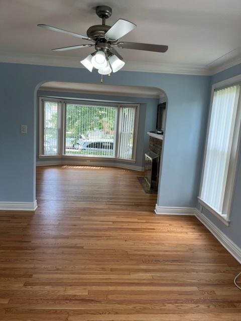 unfurnished living room featuring crown molding, a fireplace with flush hearth, wood finished floors, and baseboards