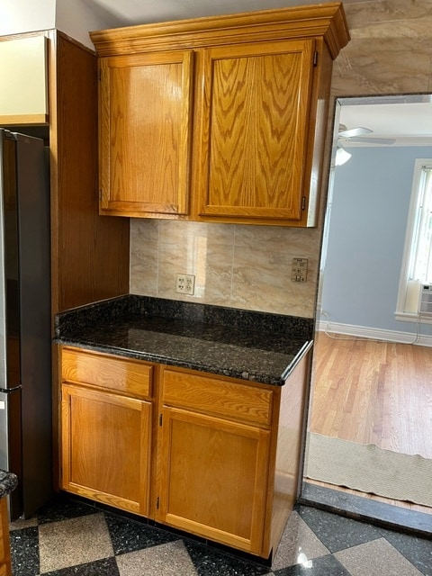 kitchen with dark stone countertops, light hardwood / wood-style flooring, stainless steel refrigerator, and ceiling fan