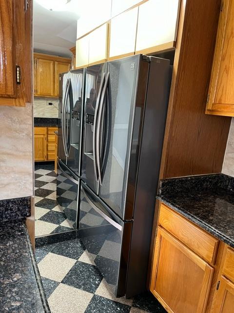 kitchen with brown cabinets, stainless steel refrigerator with ice dispenser, and dark floors