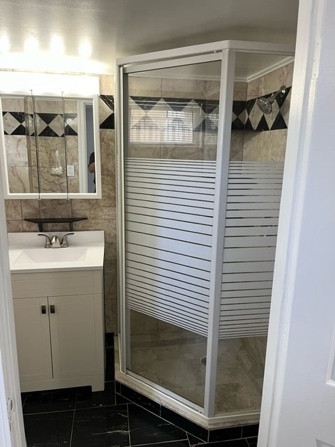 bathroom featuring a shower with shower door, vanity, and tile patterned floors