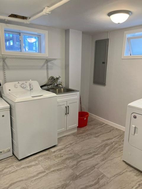 laundry area with electric panel, baseboards, a sink, and washer and clothes dryer