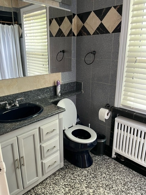 bathroom featuring tile walls, tile patterned flooring, radiator, toilet, and vanity