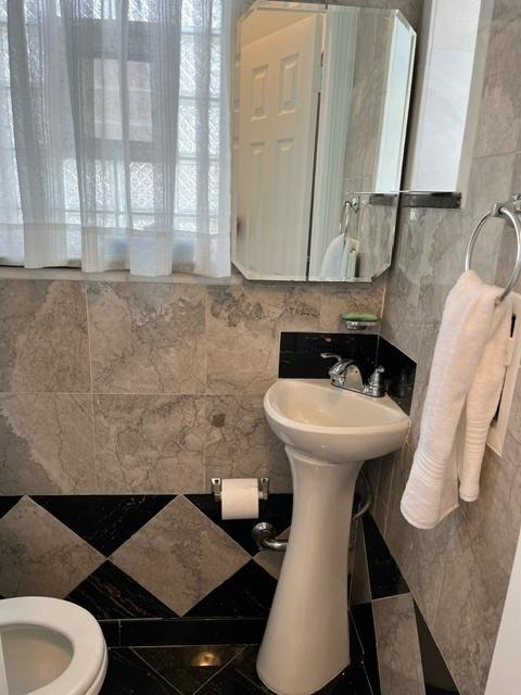 half bathroom with toilet, tile walls, and a healthy amount of sunlight