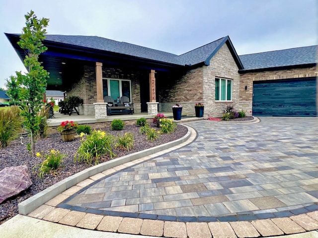 view of front facade with a garage, stone siding, roof with shingles, a porch, and brick siding