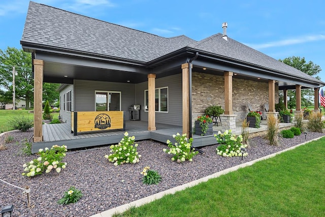 exterior space with roof with shingles and brick siding