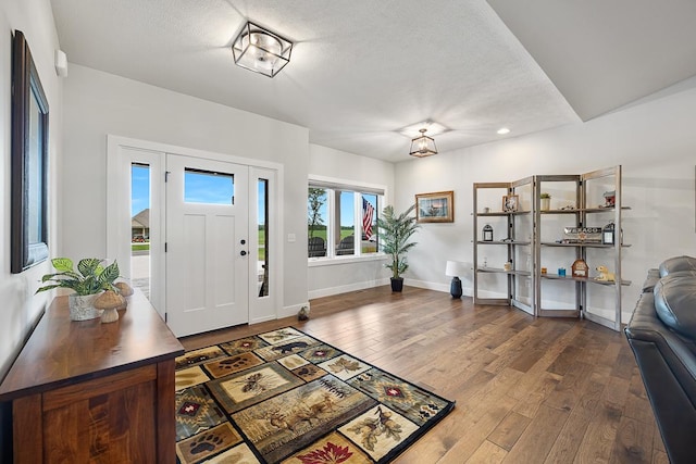 foyer entrance with a textured ceiling, dark wood finished floors, and baseboards