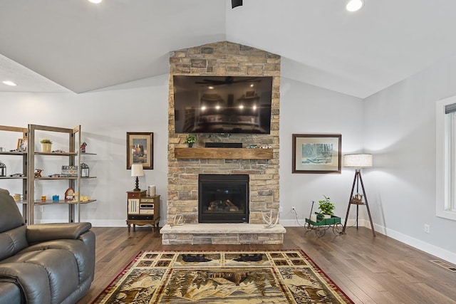 living room featuring lofted ceiling, visible vents, a stone fireplace, and wood finished floors