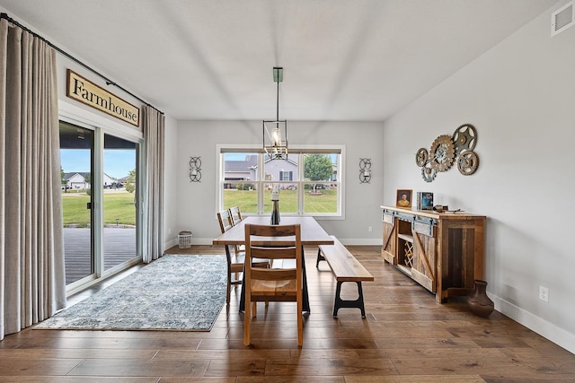 dining room featuring dark wood-style flooring, visible vents, a notable chandelier, and baseboards