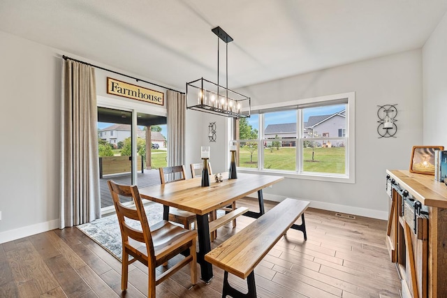 dining space with baseboards, dark wood finished floors, and a notable chandelier