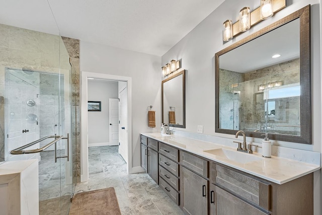 bathroom featuring double vanity, a stall shower, baseboards, and a sink