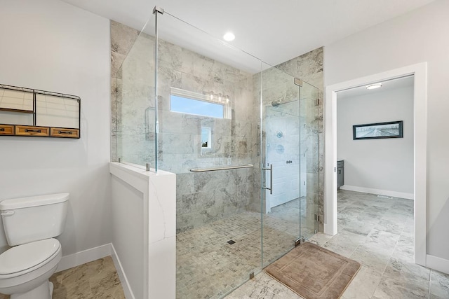 bathroom featuring a shower stall, toilet, and baseboards