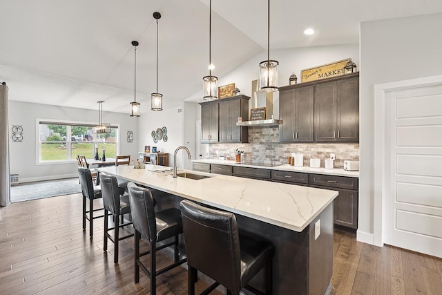 kitchen with a breakfast bar, a sink, black electric cooktop, dark brown cabinets, and backsplash